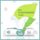 Pak Pampers Sensitive babydoekjes met plantaardige vezels, uitgelicht door een groot groen blad en 'Met PLANTAARDIGE vezels' tekst.